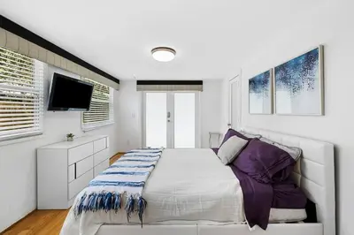 a white bedroom with a bed and a flat screen tv at Perfect FLL Location with Putting Green in Fort Lauderdale