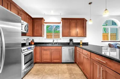 a kitchen with wooden cabinets and a stainless steel refrigerator at Center Grove - Lush & Spacious & New - 3 Bedrooms in Miami