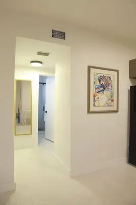 a white hallway with a painting on a wall at Apt 5 Miami Designer Apartment in the Upper East-Side in Miami