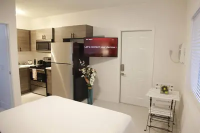 a kitchen with a refrigerator and a table with flowers in a vase at Apt 6 Miami Designer Studio in the Upper East-Side in Miami