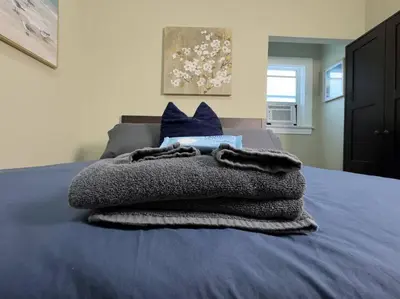 a blanket on a bed with blue sheets and blue pillows at Shenandoah Victorian Suite with TV's in every room in Miami