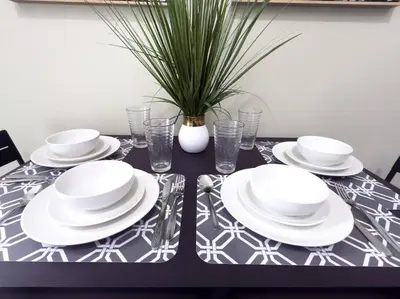 a black table with white plates and glasses and a plant at Shenandoah Victorian Suite with TV's in every room in Miami