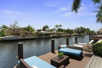 a dock with chairs and a boat on a river at Infinity Luxury Waterfront Infinity Pool and Hot Tub SLEEPS 8 in Fort Lauderdale