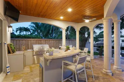 an outdoor kitchen with a kitchen island with chairs at Infinity Luxury Waterfront Infinity Pool and Hot Tub SLEEPS 8 in Fort Lauderdale