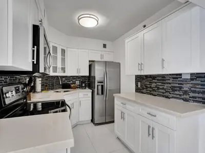 a kitchen with white cabinets and a stainless steel refrigerator at Amazing Ocean View Condo Beach Service 1111 in Miami Beach