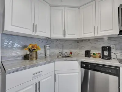 a white kitchen with white cabinets and a sink at Full ocean view Huge private terrace 1002 in Miami Beach