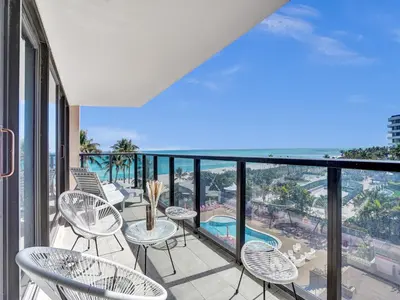 a balcony with chairs and tables and a view of the ocean at Luxury Oceanfront Condo Magnificent Views 701 in Miami Beach