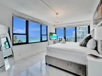 a bedroom with a large bed and large windows at Luxury Oceanfront Condo Magnificent Views 701 in Miami Beach