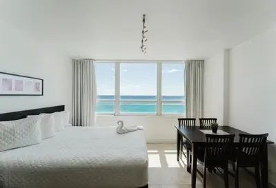a bedroom with a bed and a table and a window at Miami Beach Oceanfront in Miami Beach