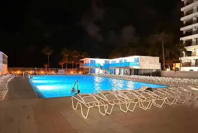 a swimming pool at night with chairs in front of a building at Miami Beach Oceanfront in Miami Beach