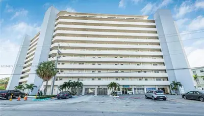 a large white building with cars parked in a parking lot at Luxurious remodeled direct Waterfront apartment with Miami skyline view- Free parking- 5min drive to Miami Beach in Miami Beach