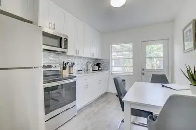 a kitchen with white cabinets and a table with chairs at Pool Free Wifi Parking Smart TV in Fort Lauderdale