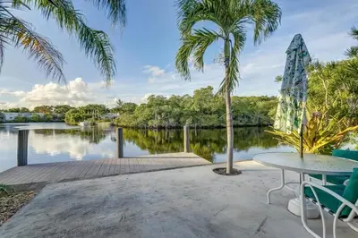 a patio with a table and palm trees and a lake at Waterfront Apartment Private Patio Pool in Fort Lauderdale