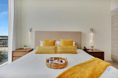 a bedroom with a large white bed with yellow pillows at Hollywood Beach Rooftop Pool Hot Tub in Hollywood