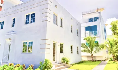 a white house with a palm tree in front of it at 12 GUESTS LUXURIOUS SOUTH BEACH SUITE 2 in Miami Beach