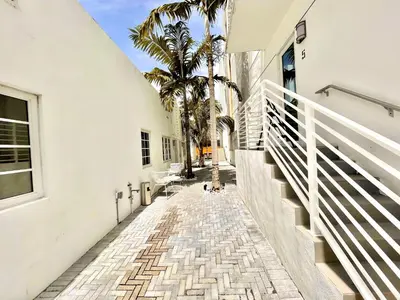 a hallway of a white building with palm trees at 16 GUESTS LUXURIOUS SOUTH BEACH SUITE WITH ROOFTOP 2 in Miami Beach