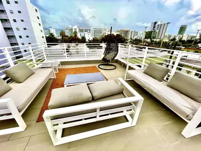 a balcony with white furniture and a city skyline at 16 GUESTS LUXURIOUS SOUTH BEACH SUITE WITH ROOFTOP 2 in Miami Beach