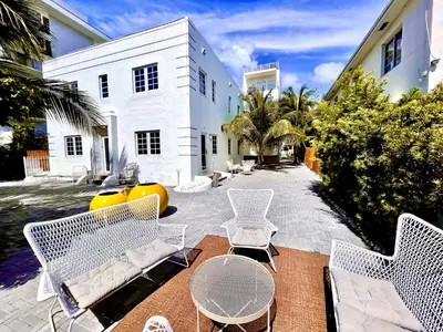 a patio with white chairs and tables and a building at 16 GUESTS LUXURIOUS SOUTH BEACH SUITE WITH ROOFTOP 2 in Miami Beach