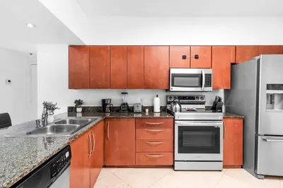 a kitchen with wooden cabinets and stainless steel appliances at Spacious 2 Bed Unit in Brickell with Free Parking in Miami