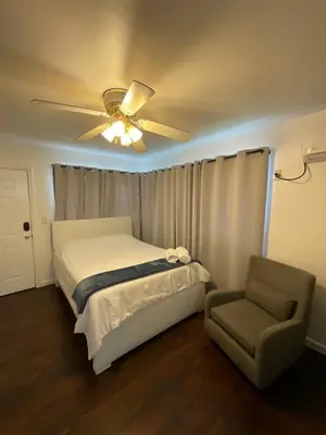 a bedroom with a bed and a ceiling fan and a chair at Private Studio Near Guitar Casino & Stadium in Carver Ranches