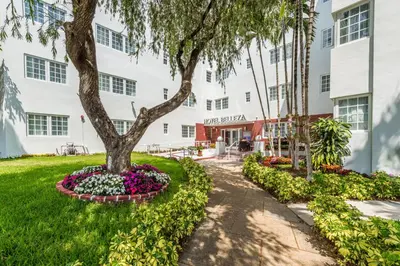 a tree in a flower bed in front of a building at Hotel Belleza in Miami Beach