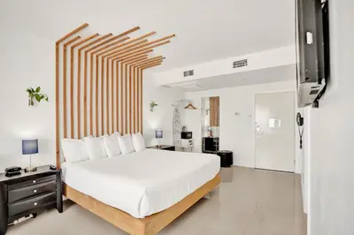 a bedroom with a large white bed with a wooden headboard at Hotel Belleza in Miami Beach