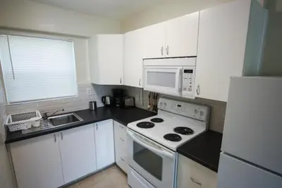a kitchen with white cabinets and a stove and microwave at Sunny Isles Apartments by MiaRentals in Sunny Isles Beach