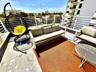 a balcony with a couch and chairs on a building at 30 GUESTS LUXURY SOUTH BEACH SUITES w ROOFTOP in Miami Beach
