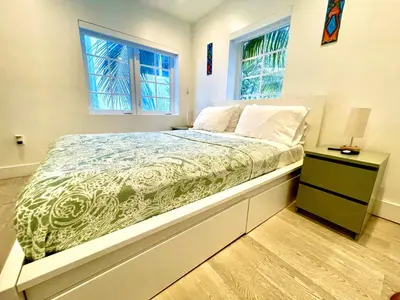 a bedroom with a bed with a nightstand and two windows at 30 GUESTS LUXURY SOUTH BEACH SUITES w ROOFTOP in Miami Beach