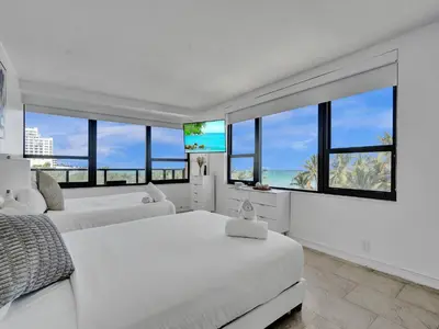 a white bedroom with two beds and large windows at Oceanfront Beach Retreat Beach Service 502 in Miami Beach