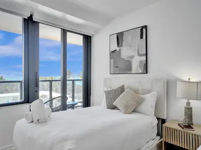 a white bedroom with a large bed and windows at Oceanfront Beach Retreat Beach Service 502 in Miami Beach