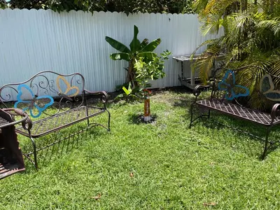 two benches sitting in the grass next to a fence at Private Cozy R/V , for your enjoyment in Tamiami