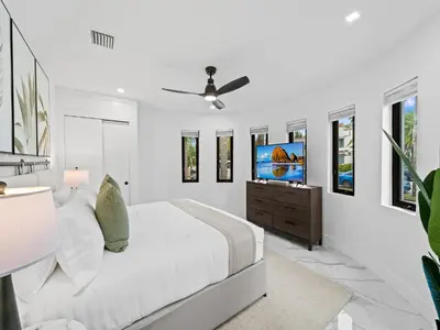 a white bedroom with a bed and a flat screen tv at Spacious home w heated pool jacuzzi in Hollywood