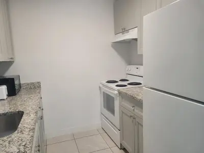 a white kitchen with a stove and a refrigerator at Arpe 4plex in Fort Lauderdale