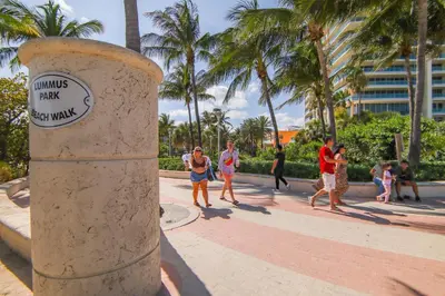 a group of people walking on a sidewalk with palm trees at Ocean Drive Prime Apt w/2 QueenBeds & Washer/Dryer in Miami Beach