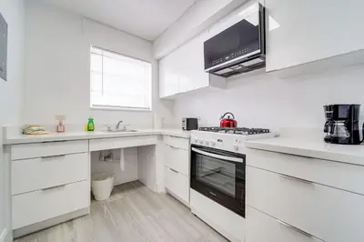 a white kitchen with a stove and a microwave at Ocean Drive Prime Apt w/2 QueenBeds & Washer/Dryer in Miami Beach