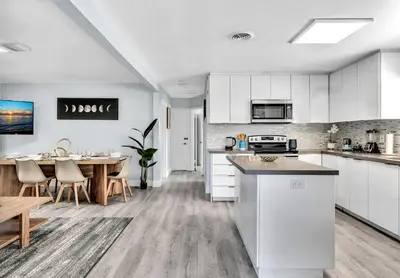 a kitchen with white cabinets and a table in it at 3br Villa W Fire Pit By Hard Rock Hotel & Casino in Fort Lauderdale
