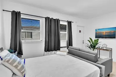 a bedroom with a bed and a couch and windows at Hollywood Blvd Near The Beach 