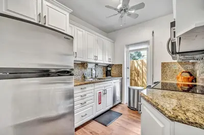 a kitchen with white cabinets and a stainless steel refrigerator at Family Escape 2BR Main plus 1BR Cottage Heated Pool in Fort Lauderdale