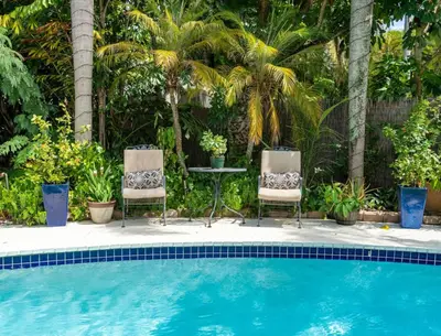 two chairs and a table next to a swimming pool at Charming Cottage 1BR, Pool, Victoria Park in Fort Lauderdale