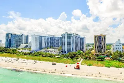 a beach with chairs and buildings and the ocean at Oceanview 1 Hotel & Homes 1 Bedroom 1 and Half Bathrooms Luxe Condo with Balcony in Miami Beach