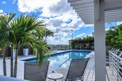 a swimming pool with chairs and palm trees on a balcony at Lovely Midblock building 1 bedroom 1 bathroom apartment in Miami