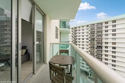 a balcony with a wooden table and chairs on a building at Tides building over the beach apartments in Hollywood