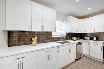 a kitchen with white cabinets and a brick wall at Luxury Villa WALK 5 minutes to Hollywood Beach in Hollywood