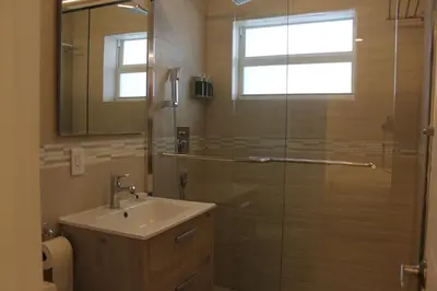 a bathroom with a shower with a sink and a mirror at Diane Oceanfront Suites in Hollywood
