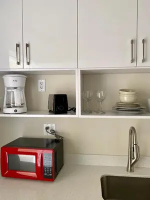 a red microwave in a kitchen with white cabinets at Diane Oceanfront Suites in Hollywood