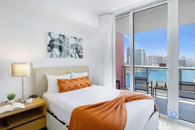 a bedroom with a bed and a large window at Spectacular Apartment Beachwalk Bliss Pool Gym in Hallandale Beach