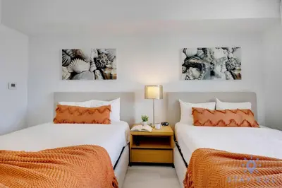 two beds with orange pillows in a bedroom at Spectacular Apartment Beachwalk Bliss Pool Gym in Hallandale Beach