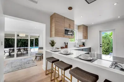 a white kitchen with a counter and stools at Samadhi - NEW 15 min drive to Ultra, by Newman Hospitality in Miami Shores