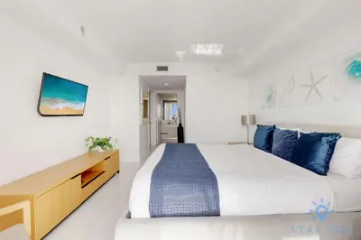a bedroom with a large bed with blue pillows at Spectacular Balcony View Retreat Resort Amenities in Hallandale Beach